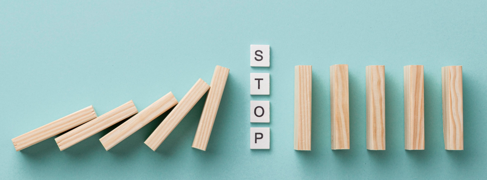 Stop and domino blocks falling on one side, standing on other side to represent risks vs benefits of outsourcing software development